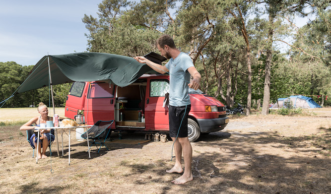 kind speelt bij waterpomp in het zand op een Natuurkampeerterrein